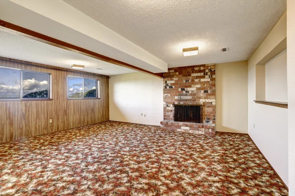 Empty living room with brick fireplace and colorful carpet floor