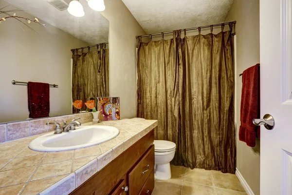 Bathroom with brown cabinet and mustard curtains