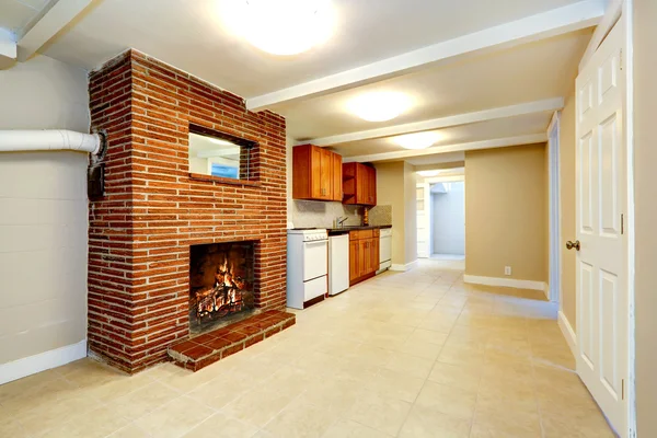 Empty basement room with brick fireplace