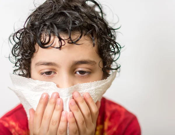 Hispanic child blowing his nose. Boy with a runny nose. Dust allergy. Kid suffering from a cold. — Stock Photo #30942867