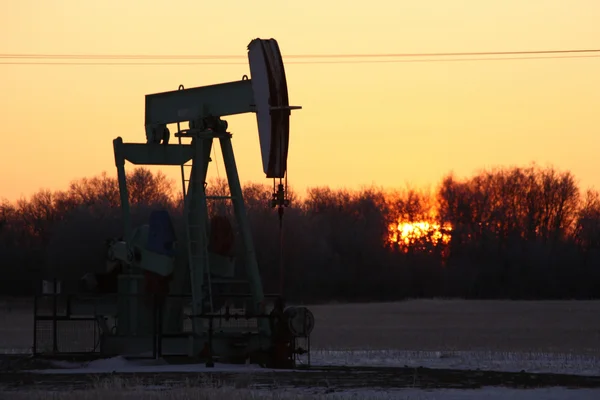 Sun rising behind oil pump jack