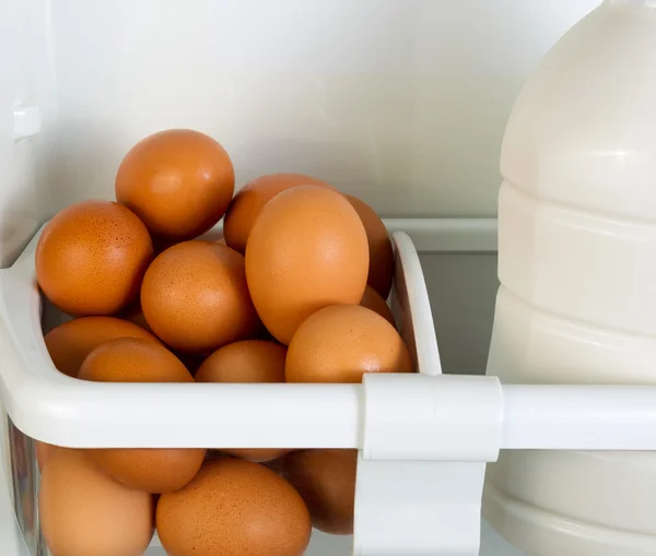 Fresh brown whole eggs and milk in refrigerator