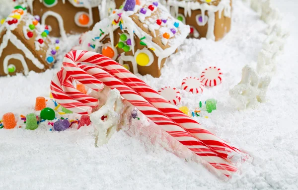 Three Red and White Candy Canes in Front of Gingerbread Houses w