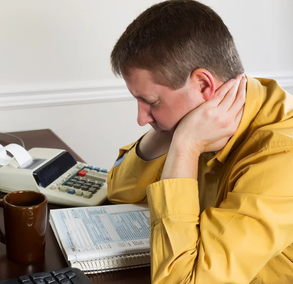 Mature man showing stress while working on his income taxes