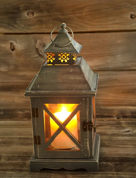 Asian Lantern and glowing white candle inside on weathered wood