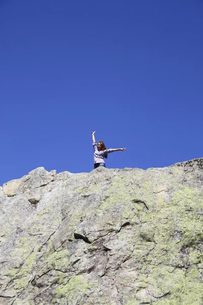 Young girl showing the peace sign on a huge rock
