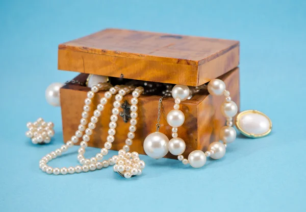 Pearl jewelry defocus in retro wooden box on blue