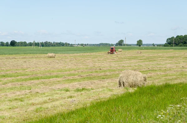 Dry haystack roll and blur tractor ted hay field