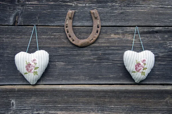 Textile cloth hearts on wooden wall and horseshoe