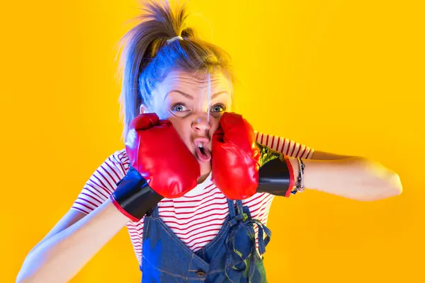 Funny fitness woman with boxing gloves, isolated on yellow