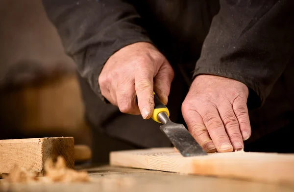 Carpenter using a chisel on a plank of wood