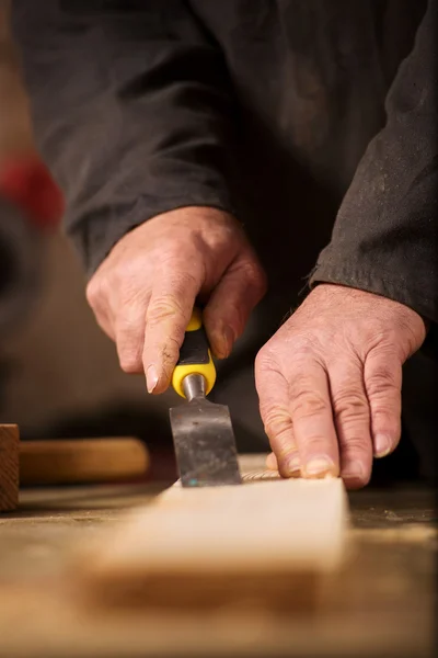 Carpenter using a chisel on a plank of wood