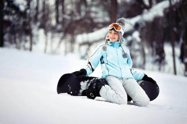 Young female snowboarder sitting