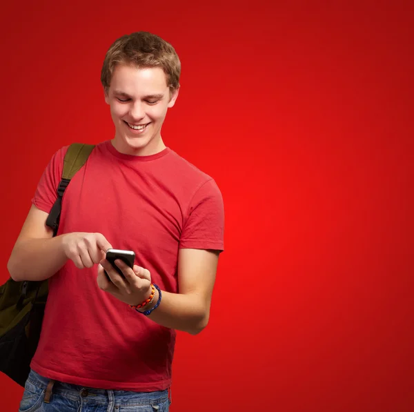 Portrait of young man touching mobile screen over red background