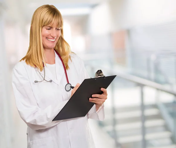 Portrait Of Happy Doctor Writing On Clipboard