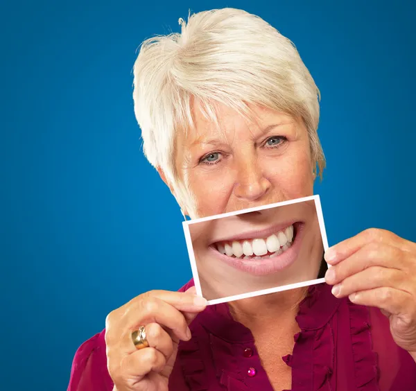Senior Woman With Manifying Glass Showing Teeth
