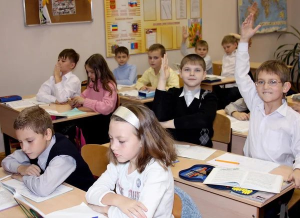 Children at school at a lesson lift hands