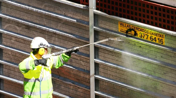 Man cleaning graffiti on a fence
