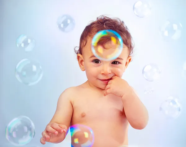 Cute baby boy playing with soap bubbles