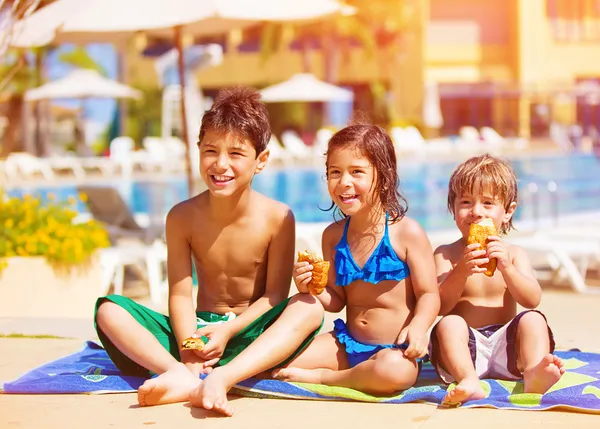 Three kids eating near pool