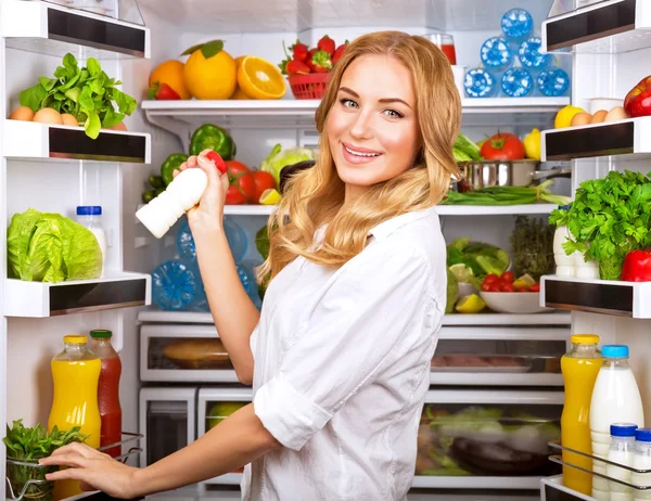 Woman chosen milk in opened refrigerator