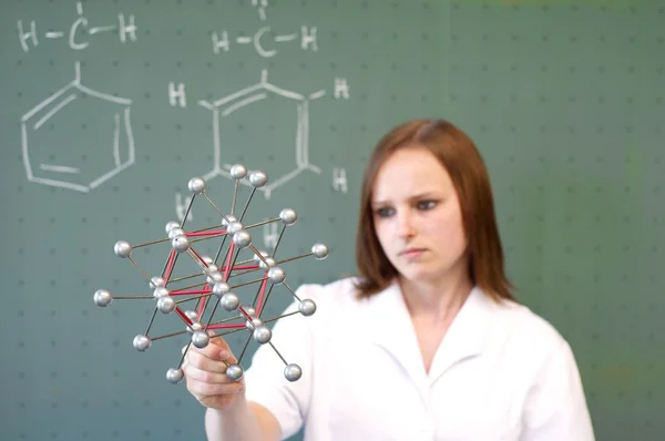 Woman analyzing molecule model in front of class