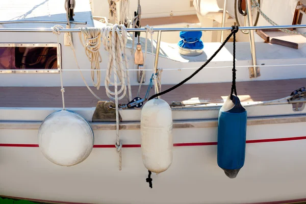 Fender buoys on sailboat side with ropes