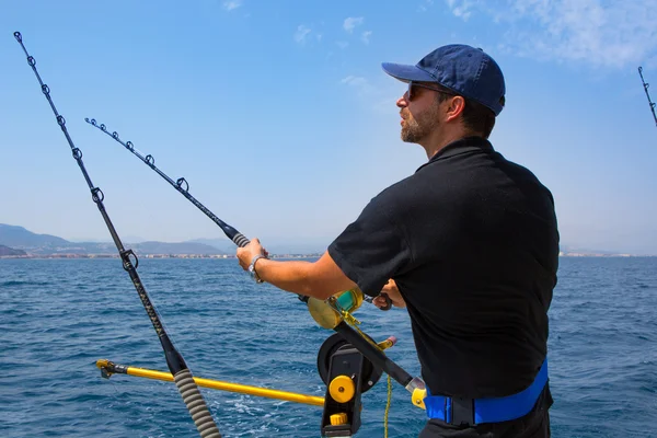 Blue sea fisherman in trolling boat with downrigger