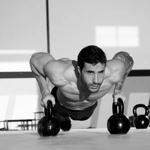 Gym man push-up strength pushup with Kettlebell