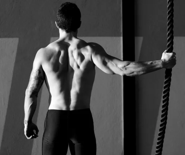 Crossfit gym man holding hand a climbing rope
