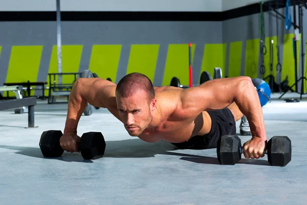 Gym man push-up strength pushup exercise with dumbbell