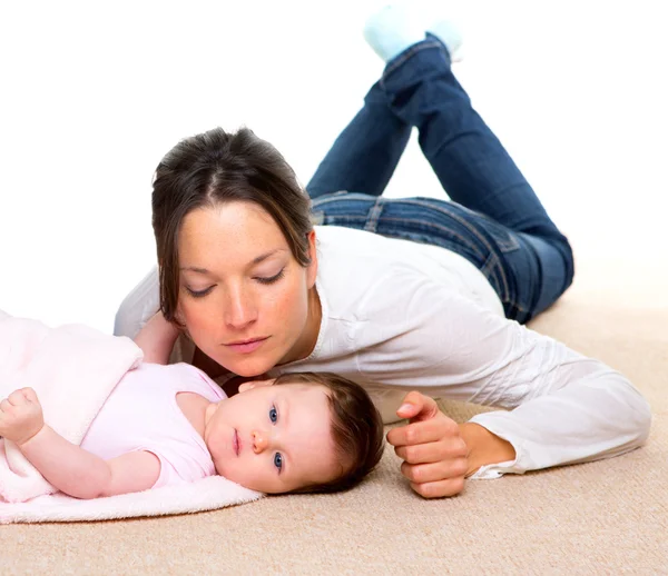 Baby and mother lying on beige carpet together