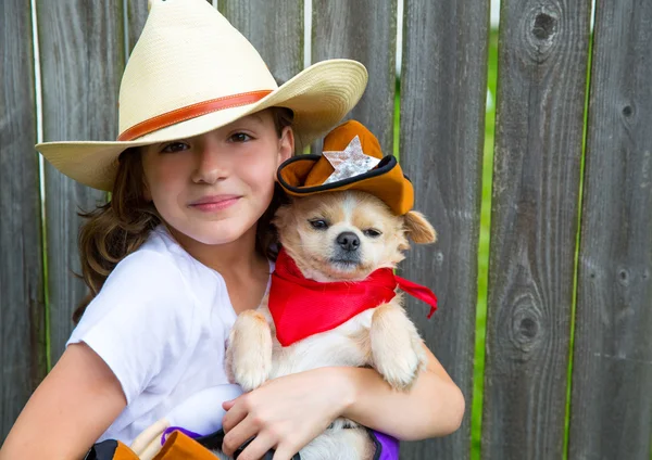 Beautiful cowboy kid girl holding chihuahua with sheriff hat