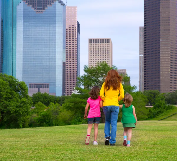 Mother and daughters walking holding hands on city skyline