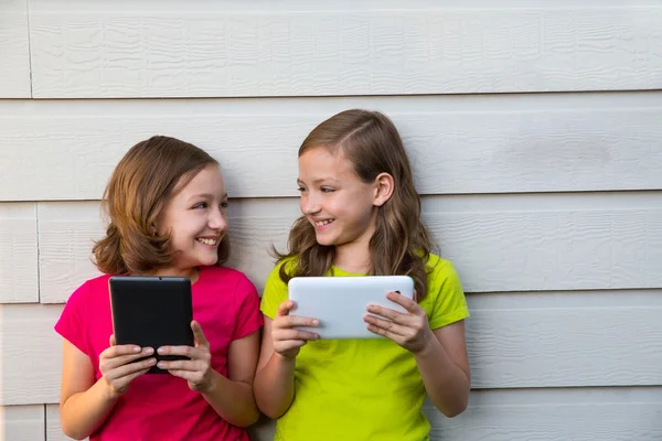 Twin sister girls playing with tablet pc happy on white wall