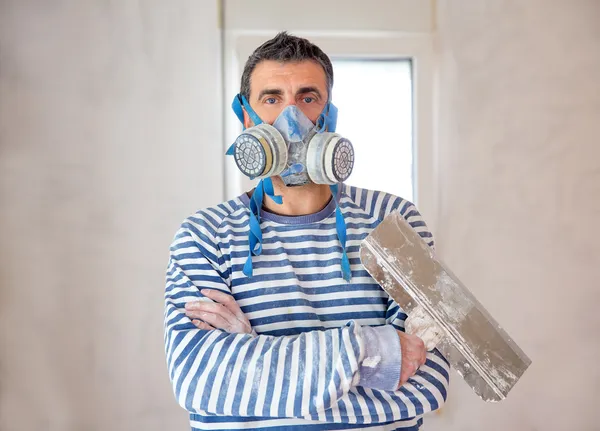 Funny plastering man mason with protective mask and trowel