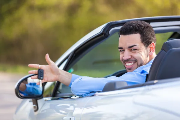 Young black latin american driver holding car keys driving his n