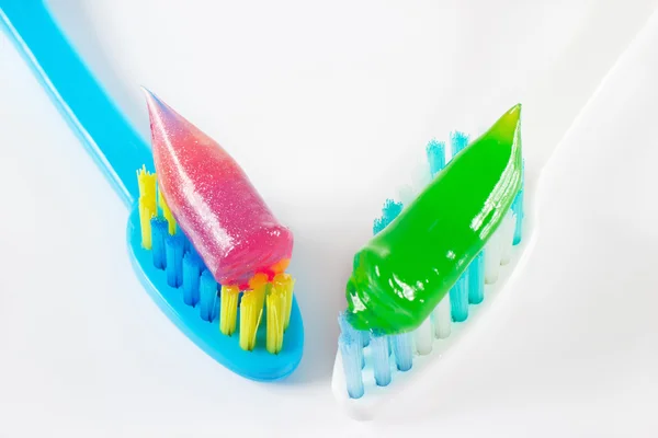 White and blue toothbrushes with gel toothpaste on a white backg