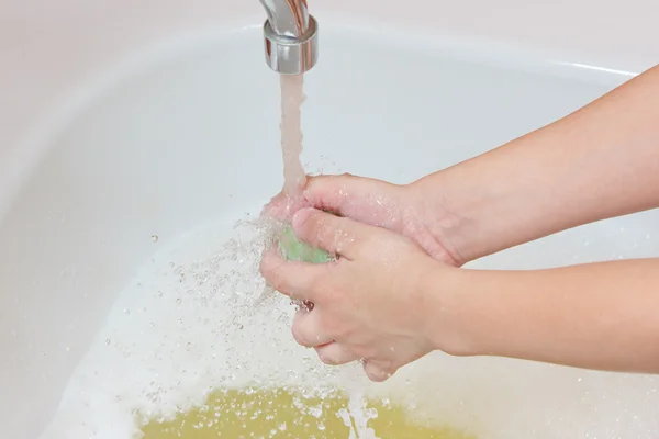 Washing children\'s hands with soap under the faucet in bathroom