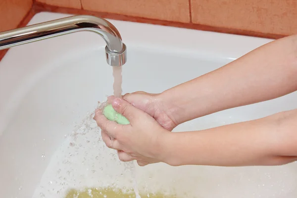 Washing children\'s hands under the faucet in bathroom