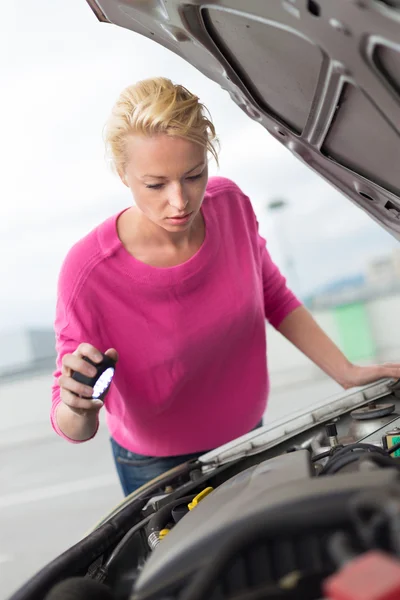 Woman inspecting broken car engine.