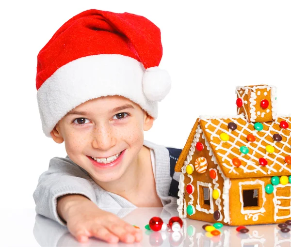 Little boy in Santa's hat with gingerbread house