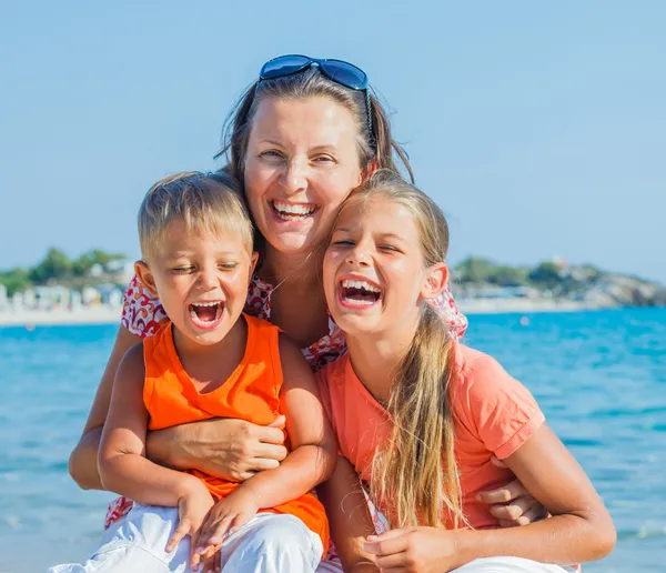 Portrait of happy family laughing and looking at camera on the beach