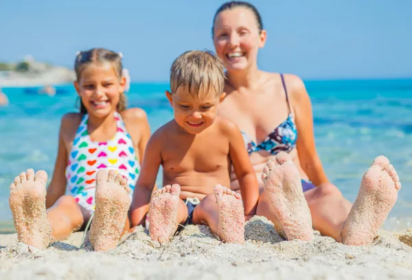 Summer beach - family playing on sandy beach. Focus on the feet and boy.