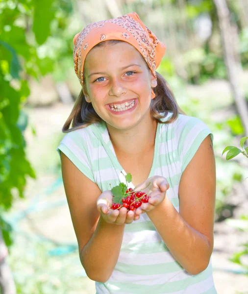 Young girl holding in hand organic natural healthy food produce - red currant. Focus on the red currant. Vertical view