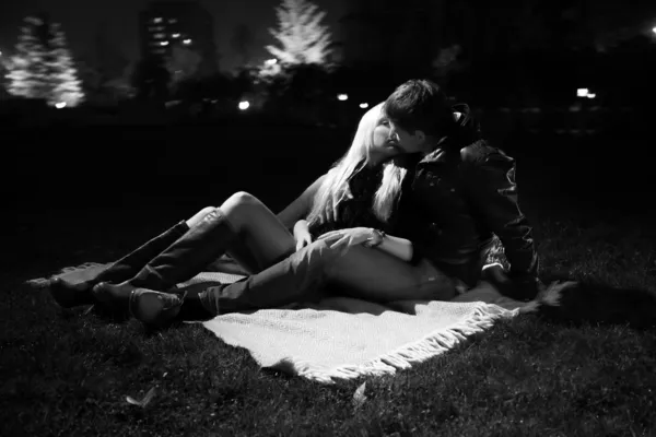 Couple hugging on grass in park at night