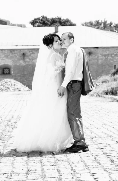 Portrait of bride and groom kissing on paving road