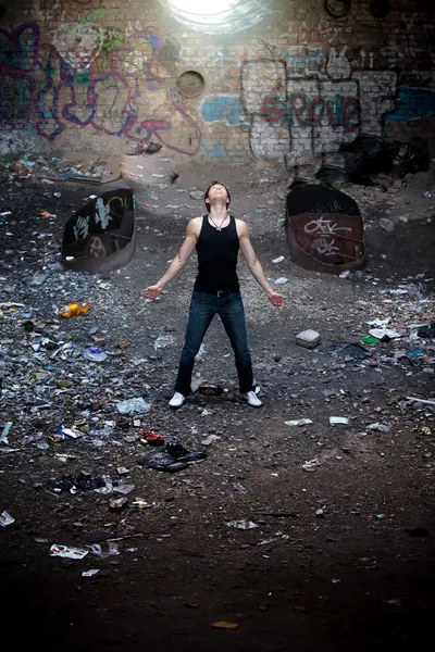 Man in black singlet standing in ruined tunnel and looking up