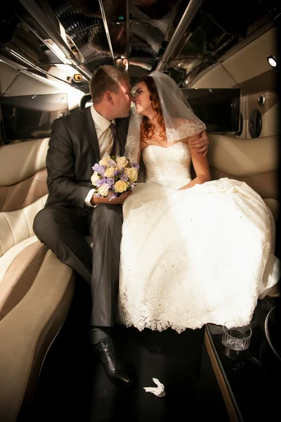 Newly married couple kissing on back seat of limousine