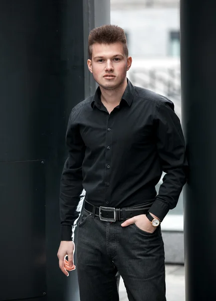 Man in black shirt and trouser posing on street
